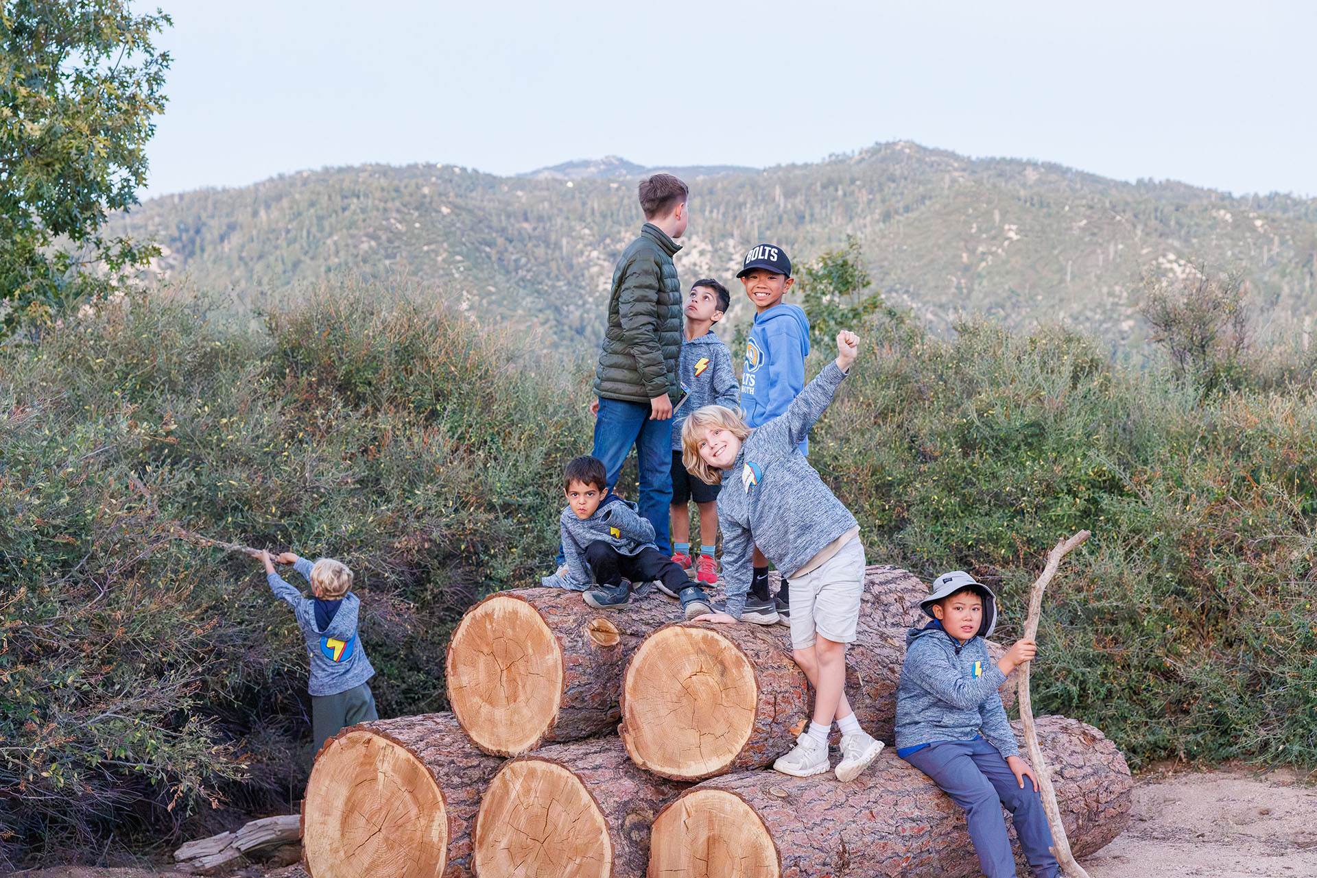 Lightning Bolts boys in their camp hoodies posing on a stack of logs at Pali