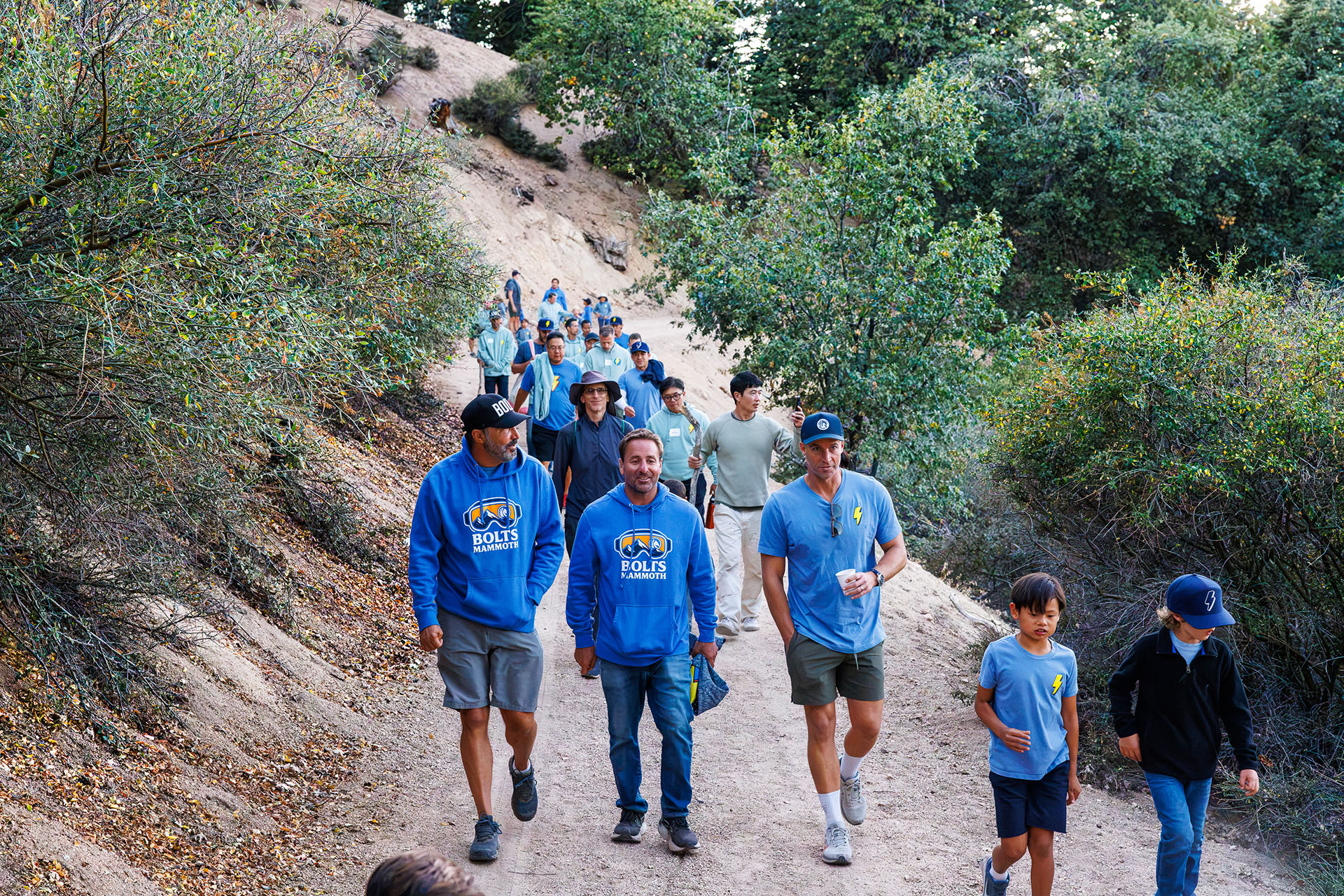 Lightning Bolts dads and boys hiking together along a wooded trail at Pali